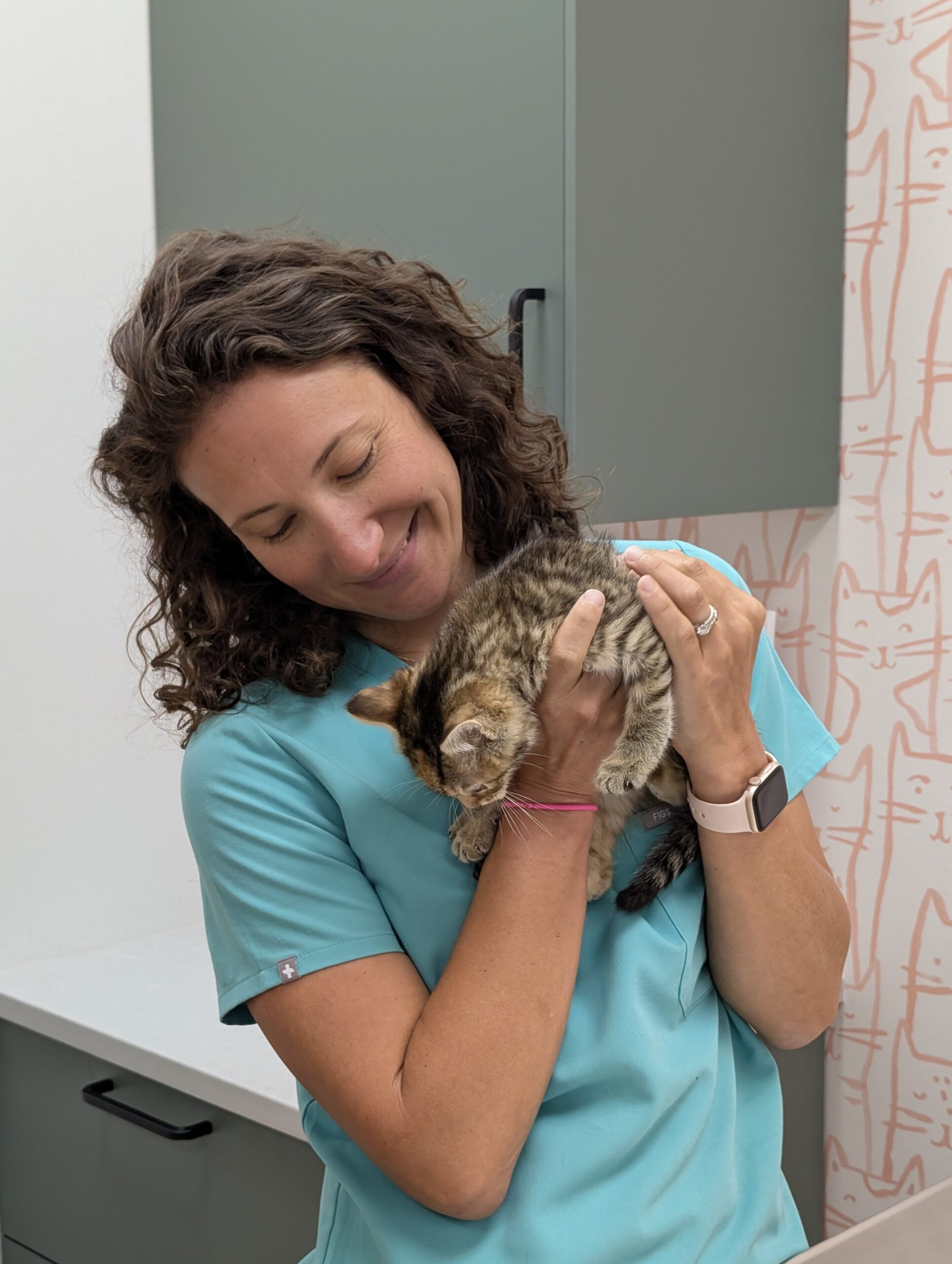 Dr. Thomas gently snuggling a small kitten in a warm and caring veterinary setting.