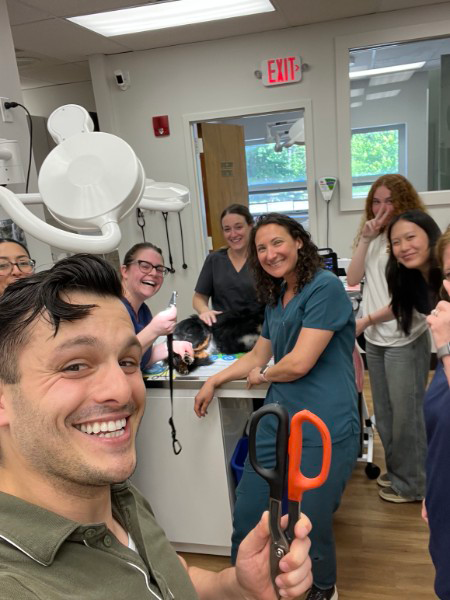 Andrew from Mount Kisco Supply holding heavy-duty shears beside the Healing Paws Veterinary Center team during a dog paw emergency procedure.